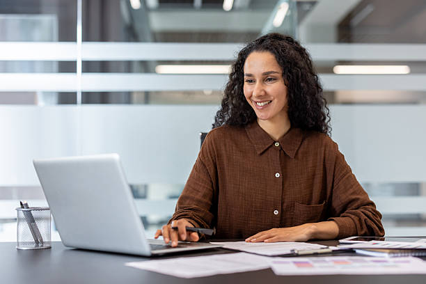 istock Professional Woman Smiling While Working on Laptop in Modern Office Workspace 2245818149