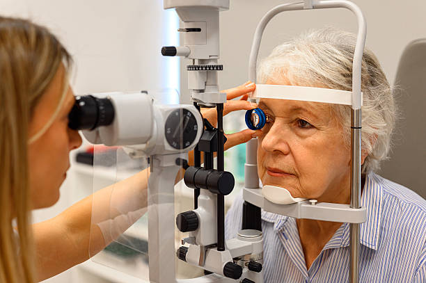 istock Female ophthalmologist using diagnostic lens during slit lamp test to examine senior woman's eyes at clinic 2245818192