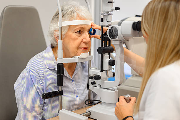 istock Female ophthalmologist examining senior woman's eyes with slit lamp while holding diagnostic lens in clinic 2245818202