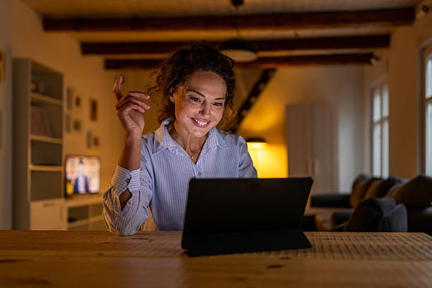 istock Smiling Woman Using Tablet at Home, Cozy Living Room Setting with Warm Lighting 2245818216
