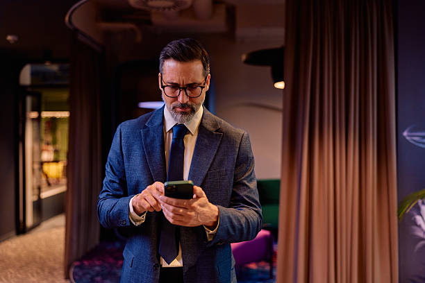 istock Mature businessman checking mobile phone indoors 2245818519