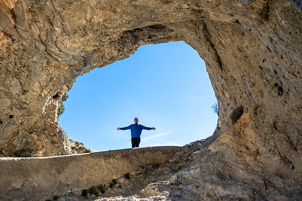 Man with outstretched arms standing inside a natural rock formation in cuenca, spain