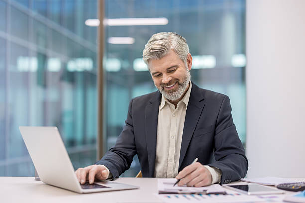 istock Senior businessman working on laptop researching financial data 2245823868