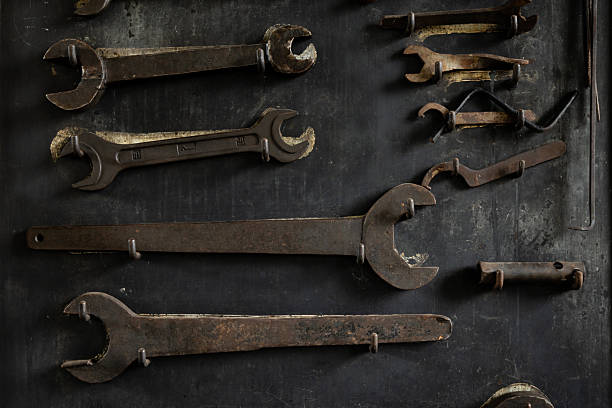 Large industrial wrenches and spanners arranged on hooks in an old workshop.
