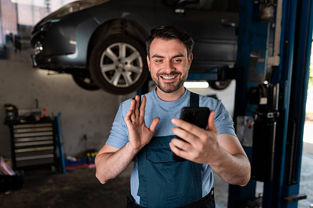 istock Mechanic smiles while talking on smartphone in busy garage during the day 2245830492