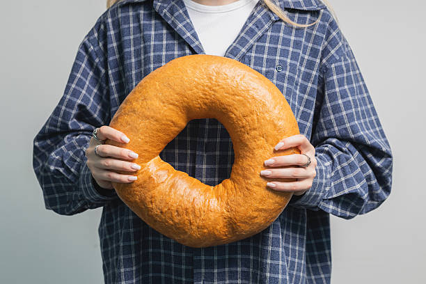 istock Woman in plaid shirt holding large round bagel 2245834026