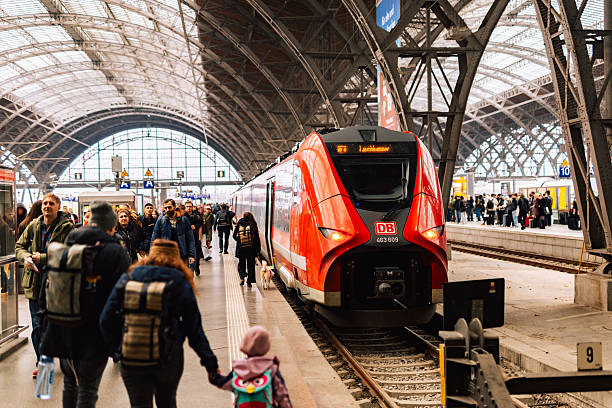 Leipzig, Germany – November 8, 2025: Red Deutsche Bahn regional train stands at Leipzig Hauptbahnhof under the historic glass roof with many passengers on the platform.