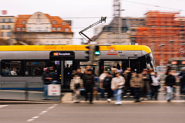Leipzig, Germany – November 8, 2025: Tram line 16 operated by Leipziger Verkehrsbetriebe seen near Leipzig Hauptbahnhof with passengers crossing the street and blurred motion of people and vehicles.