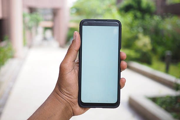 istock Holding a smartphone in a sunny outdoor location 2245844170