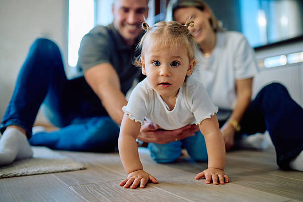 istock Baby girl crawling learning supported by loving parents 2245845108
