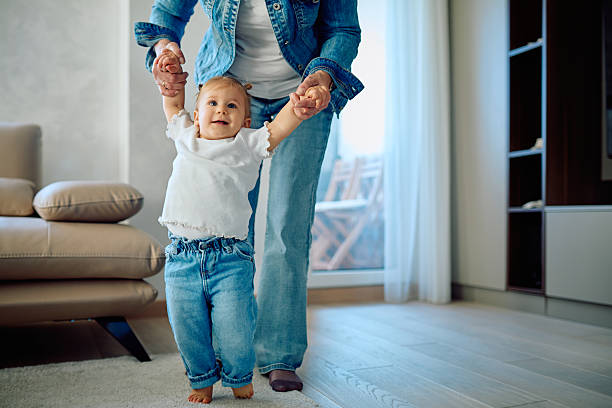 istock Mother helping happy baby taking first steps 2245845110