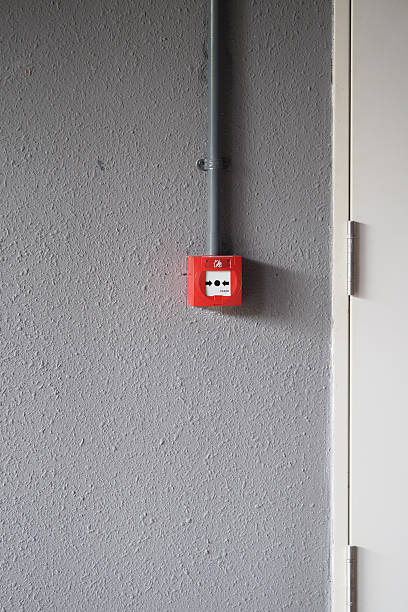 istock Fire alarm mounted on a gray wall near a door 2245846194