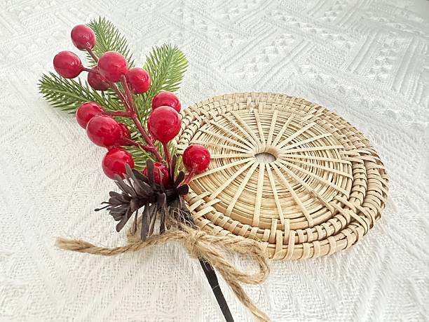 istock Decorative wicker fan with red berries and greenery on a textured white fabric background for home decor and seasonal arrangements 2245851071