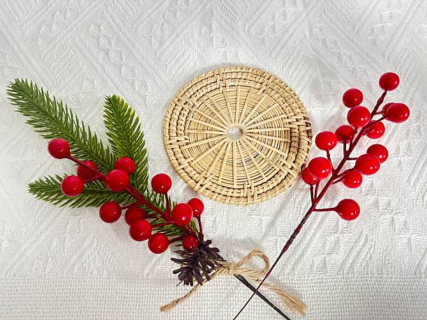 istock Red Berries and Green Leaves on Woven Basket Placed on Textured White Background for Rustic Holiday Decoration 2245851074