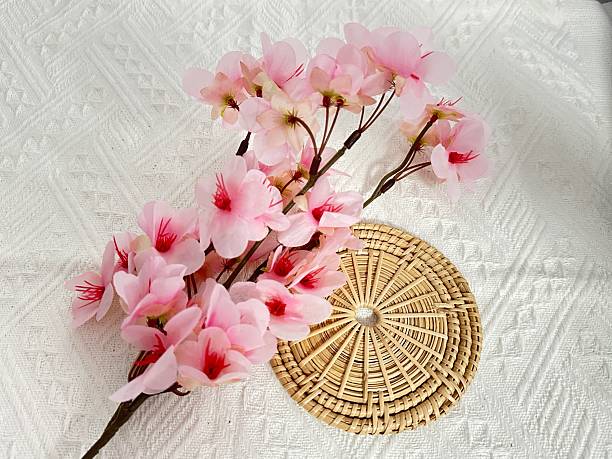 istock Delicate pink cherry blossom flowers arranged on textured white fabric with woven circular plate underneath, displaying natural beauty and elegance 2245851333