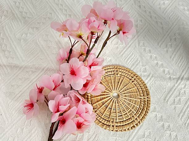 istock Delicate Pink Artificial Flowers Arranged on Natural Woven Placemat with Elegant Texture and Soft Colors for Home Decor and Floral Arrangement Projects 2245851337