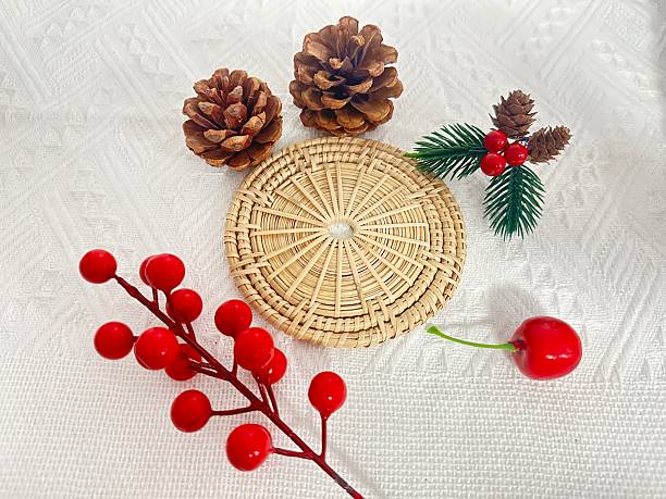 istock Natural Decorative Elements with Pine Cones, Red Berries, and Wicker Coaster on White Textile Background for Seasonal Festivities 2245852206