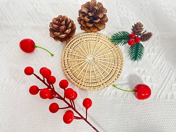 istock Decorative Arrangement Featuring Pine Cones, Red Berries, Green Leaves, and a Woven Coaster on a Textured White Background for Seasonal Decor 2245852231