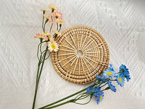 istock Elegant display of woven coaster and artificial flowers on textured background, adding charm and color to home decor and interior design setups 2245852349