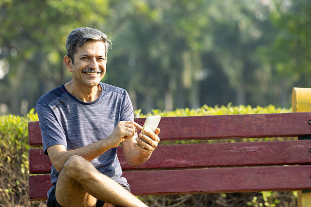 istock Indian Senior Man Sitting on Park Bench Using Smartphone to Relax After Exercise 2245853133
