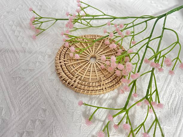 istock Delicate pink flowers arranged on a textured white background with a round woven mat, creating an elegant and serene atmosphere for natural decor photography 2245853270