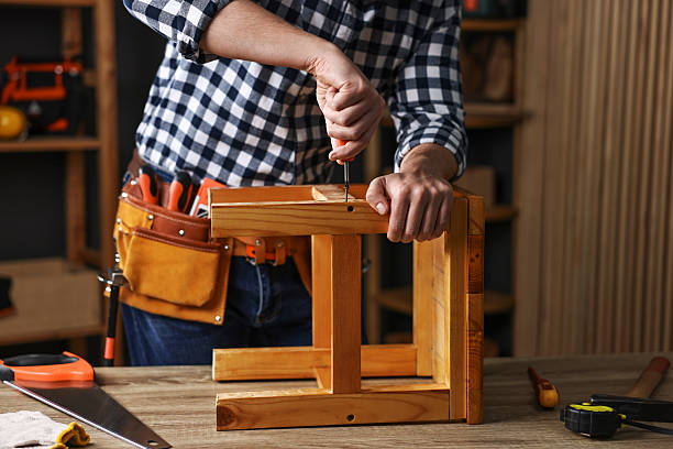 Carpenter repairing stool at table in workshop, closeup
