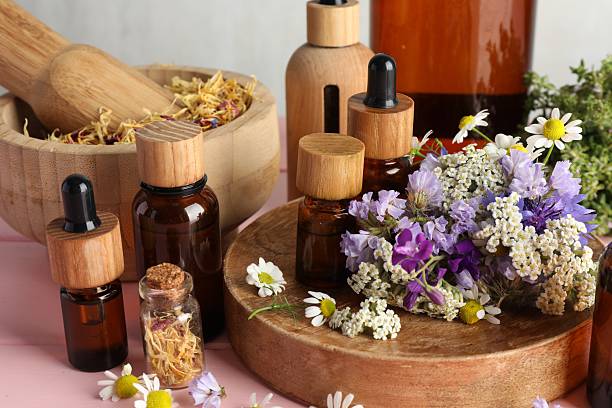 istock Aromatherapy. Different essential oils, mortar, pestle and flowers on pink wooden table 2245862641