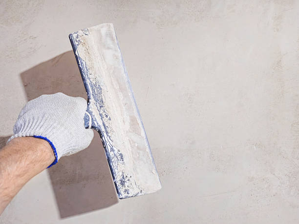istock Male hand holds putty and putties the wall. 2245863226