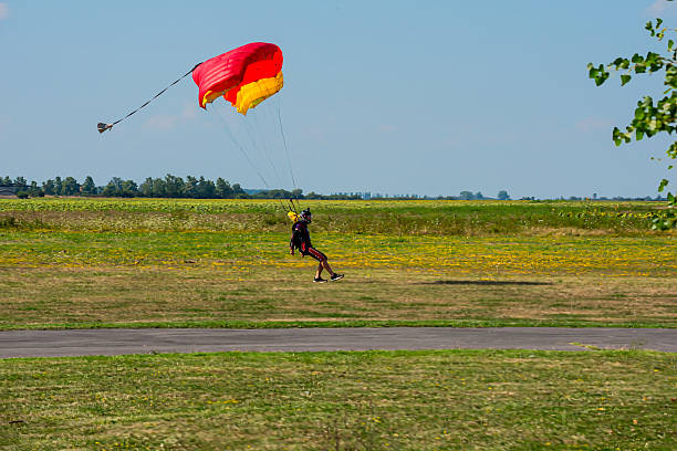 istock Skydiver With Colorful Parachute Lands on Open Field Under Bright Blue Sky 2245866906