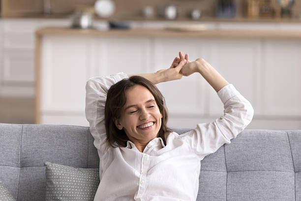 istock Serene young lady enjoy home relaxation stretch arms on couch 2245867356