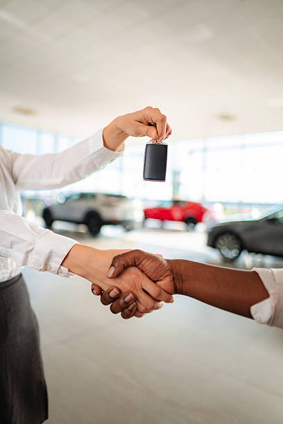 istock Car salesman handing keys shaking hands with customer 2245869145