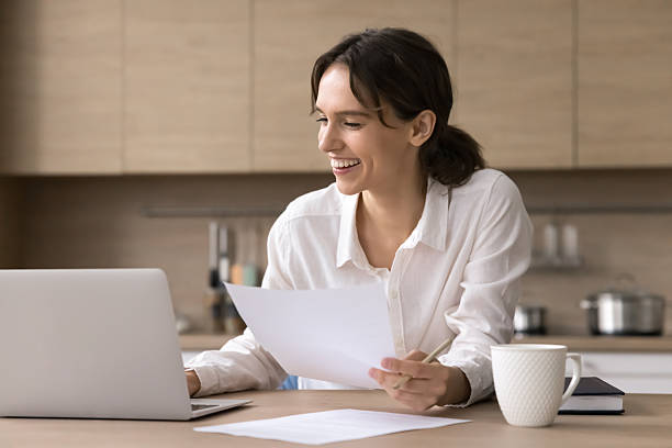 istock Smiling young woman freelance worker engaged in paperwork using notebook 2245870815
