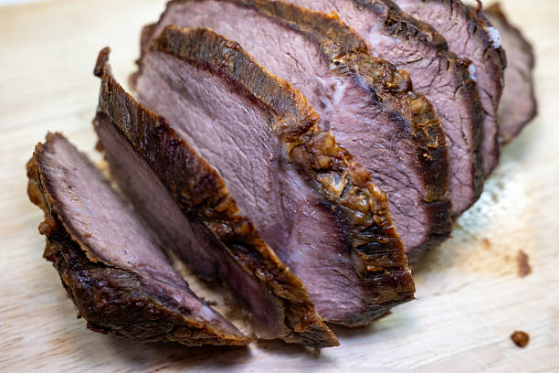 Close-up of delicious, tender sliced roast beef on a wooden cutting board. Perfectly cooked meat with a crispy crust, ready for a savory dinner.