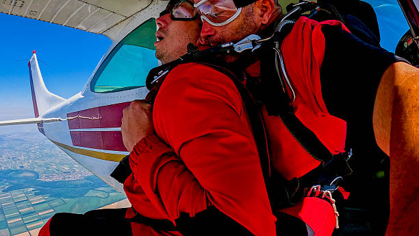 Tandem skydivers capture an adrenaline-fueled selfie during freefall with a canopy ride above the landscape