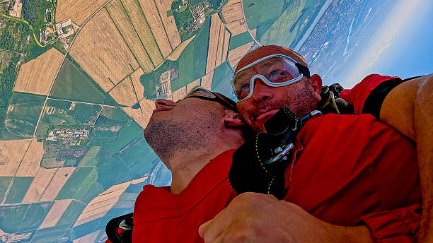 Two skydivers in tandem freefall share a selfie during adrenaline-fueled jump from a plane