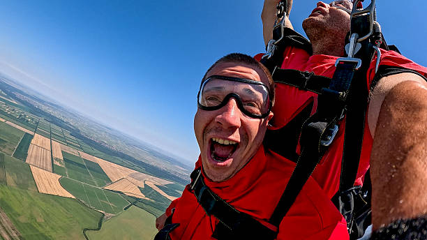 istock Tandem skydivers take a selfie during freefall with wrist-camera and dramatic landscape below 2245872308