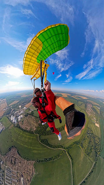 istock Tandem skydiving moment: two riders under a bright canopy, soaring over landscapes in freefall 2245872331