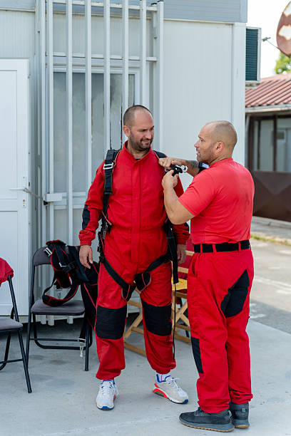 istock Instructor helps student fit harness and check gear before tandem skydiving training session 2245873994