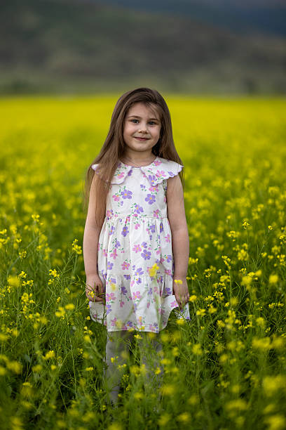 A Little Girl Smelling Dandelions in a Field of Green
