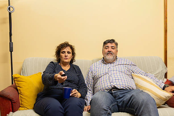 istock Middle aged couple relaxing on sofa watching television 2245877396