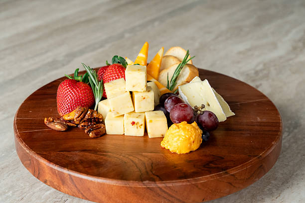 Gourmet Cheese Board with Fresh Fruit Nuts and Herbs on Wood Platter