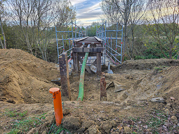 istock building a bridge foundation in a countryside setting. Scaffolding surrounds the under-construction structure, with tools and dirt scattered around. 2245879239