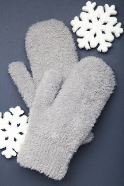 Winter grey mittens with snowflakes on dark blue background, warm mittens. Top view
