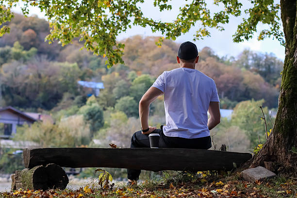 istock Backlit man with coffee enjoying fall woodland vista on bench 2245887589