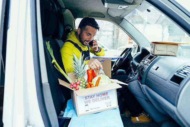 istock Delivery man talking on phone with grocery box in van 2245888538