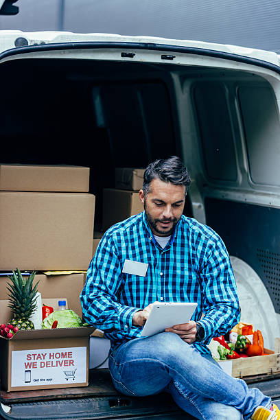 istock Delivery man using tablet preparing for grocery delivery 2245888597