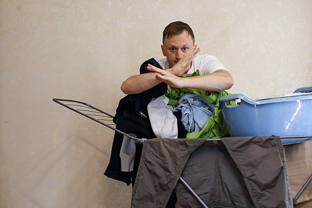 istock Young man shushing gesture near laundry rack with clothes and blue basket (62 chars) 2245888600