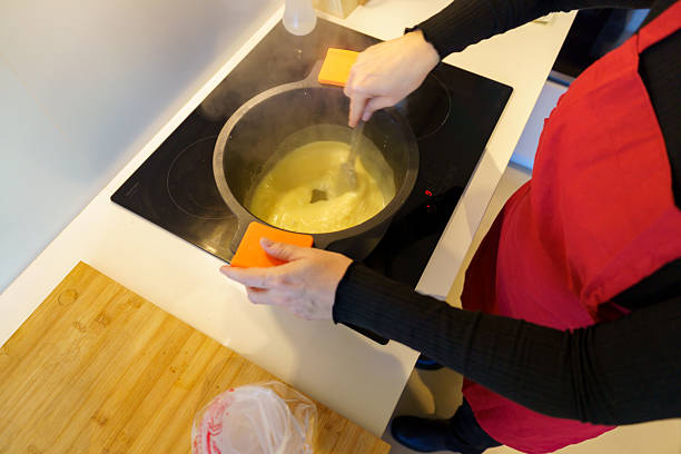Woman in red apron cooking soup while stirring it on an induction stovetop