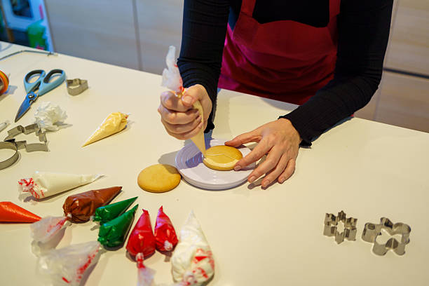 istock Woman decorating sugar cookies with white icing using a pastry bag 2245889762