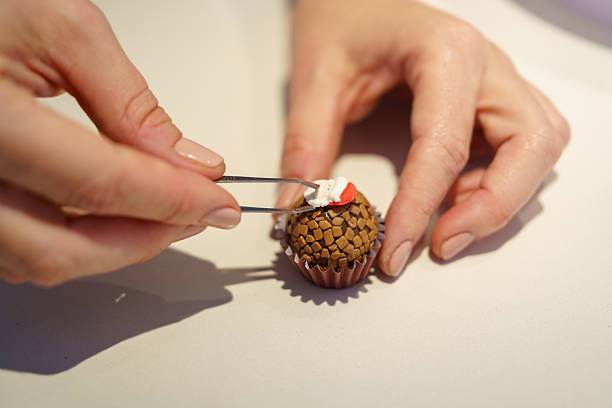 Person using tweezers decorating a brigadeiro with a small santa claus hat